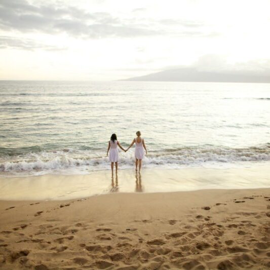 2 women walking on the beach in sunset