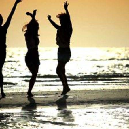 3 women dancing during sunset at the beach